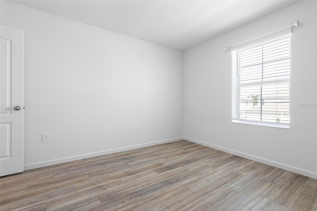 spare room featuring light wood finished floors and baseboards