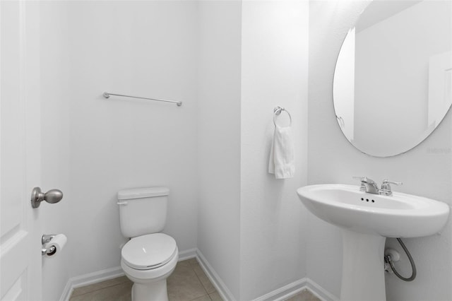 half bath featuring tile patterned floors, toilet, and baseboards