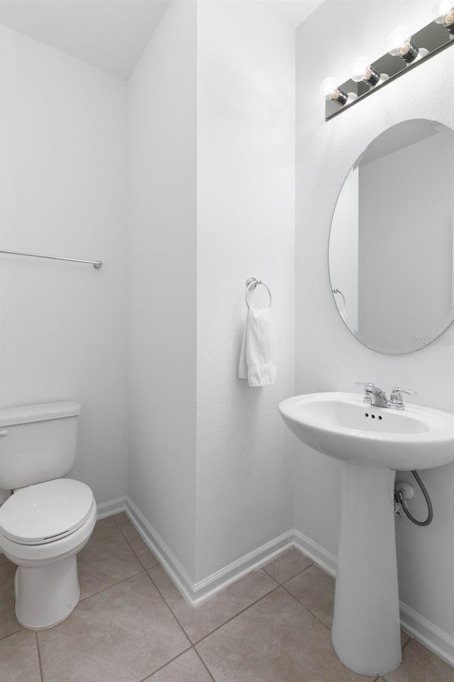 bathroom with tile patterned floors, baseboards, toilet, and a sink