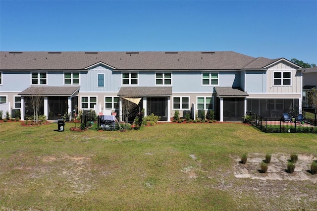 back of property with fence, a sunroom, a shingled roof, a lawn, and board and batten siding