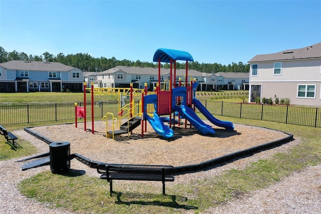 community jungle gym featuring a residential view, a lawn, and fence