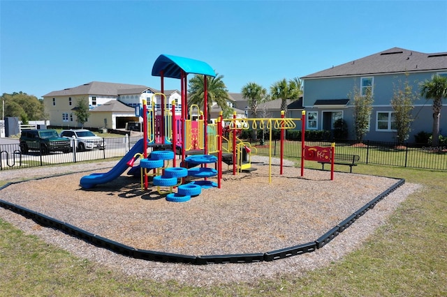 communal playground featuring a residential view, a lawn, and fence