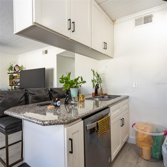 kitchen with visible vents, dishwasher, white cabinets, stone countertops, and a sink