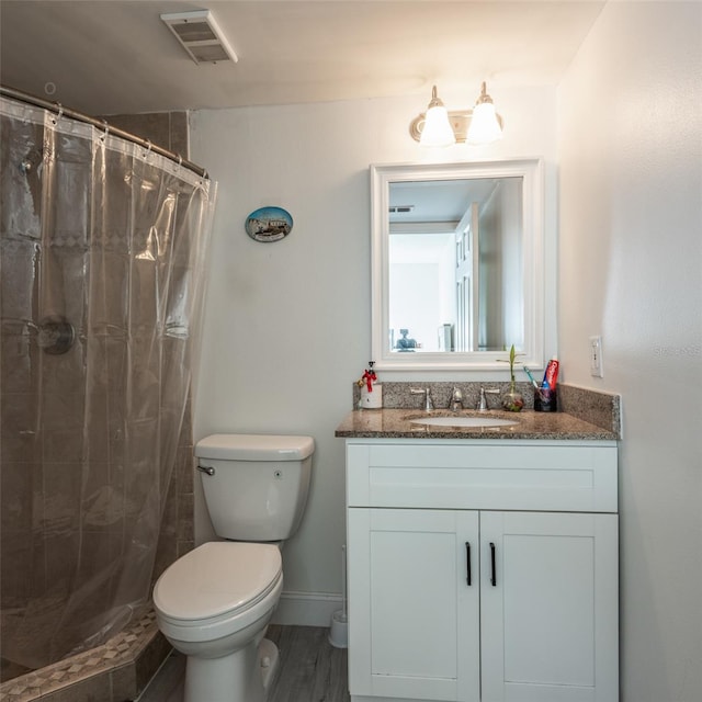 bathroom featuring visible vents, baseboards, toilet, tiled shower, and vanity