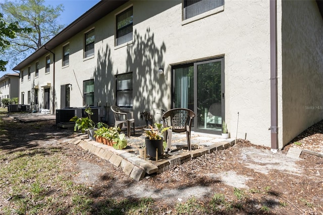 back of house with central AC unit and stucco siding