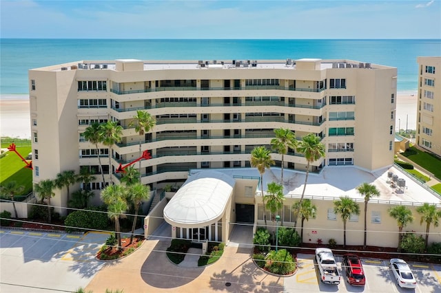 view of building exterior with uncovered parking and a water view