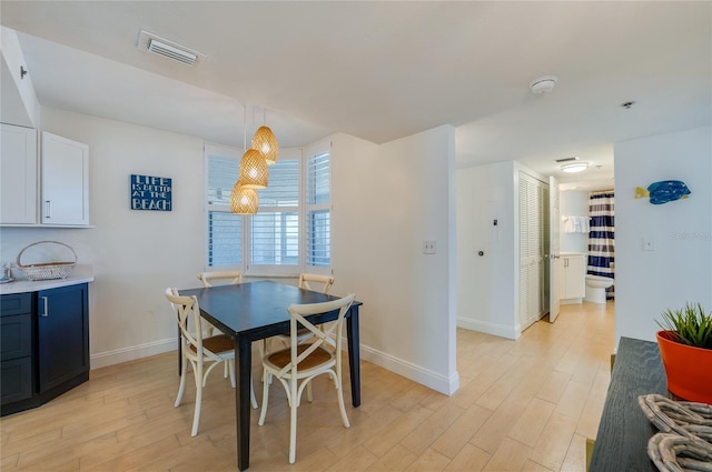 dining space with light wood-type flooring, baseboards, and visible vents