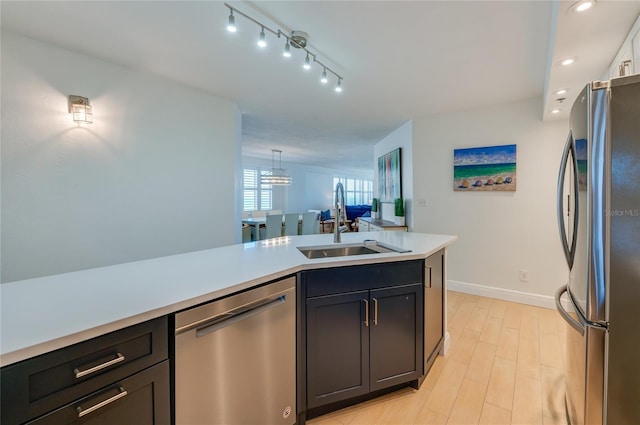 kitchen with a sink, stainless steel appliances, light wood-style floors, light countertops, and baseboards