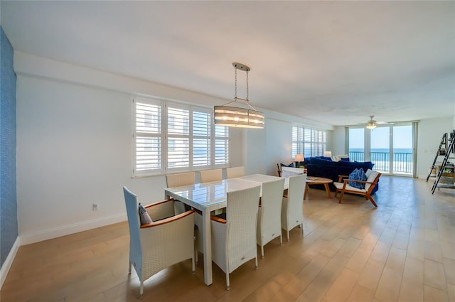 dining space with baseboards, light wood-type flooring, and a ceiling fan