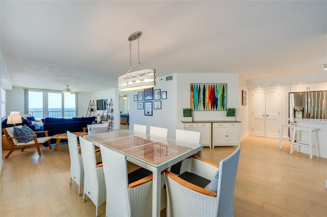 dining space featuring light wood finished floors, visible vents, and a ceiling fan