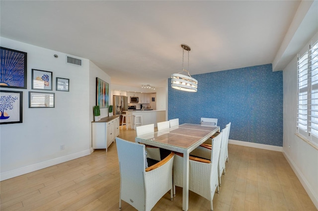 dining room with wallpapered walls, baseboards, visible vents, and light wood finished floors