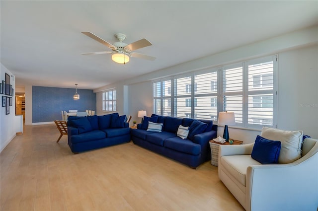 living room featuring light wood-type flooring, baseboards, and a ceiling fan