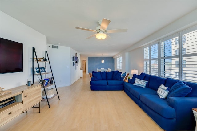 living area with baseboards, a ceiling fan, visible vents, and light wood-type flooring