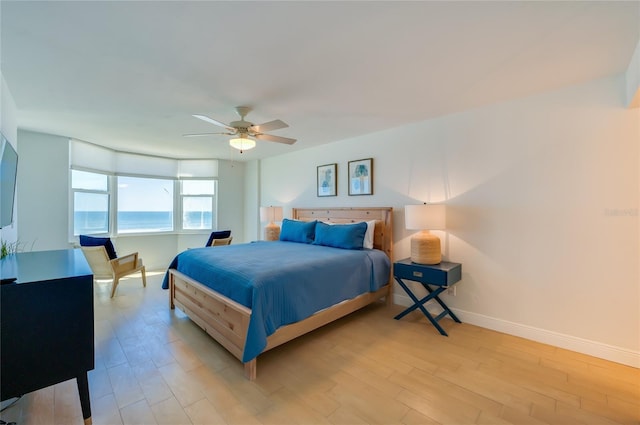 bedroom with baseboards, light wood-style flooring, and a ceiling fan