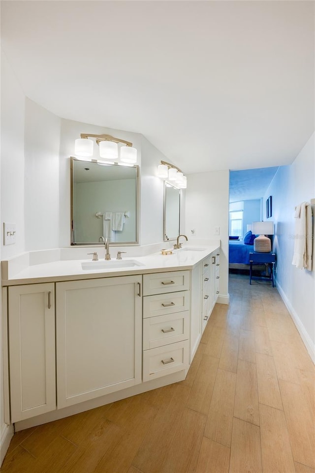 bathroom with double vanity, wood finished floors, and a sink