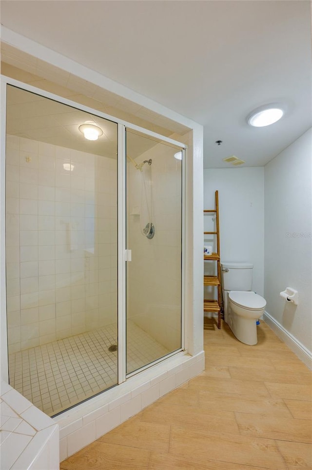 bathroom featuring visible vents, baseboards, toilet, a stall shower, and wood finished floors