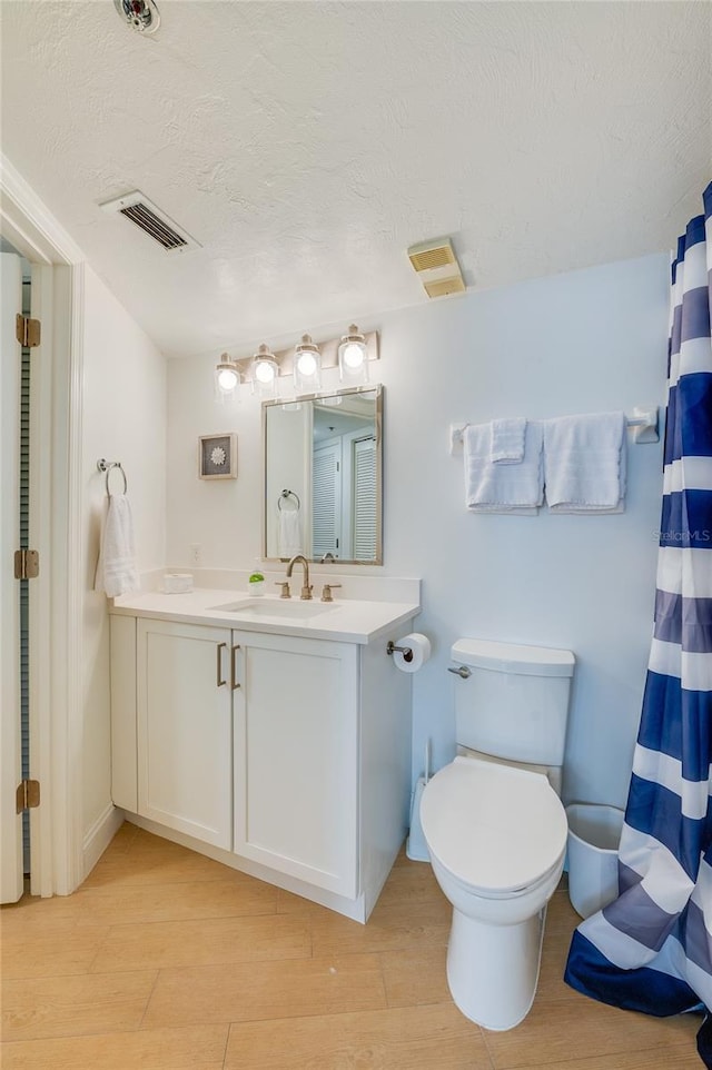 full bath featuring visible vents, toilet, a textured ceiling, wood finished floors, and vanity