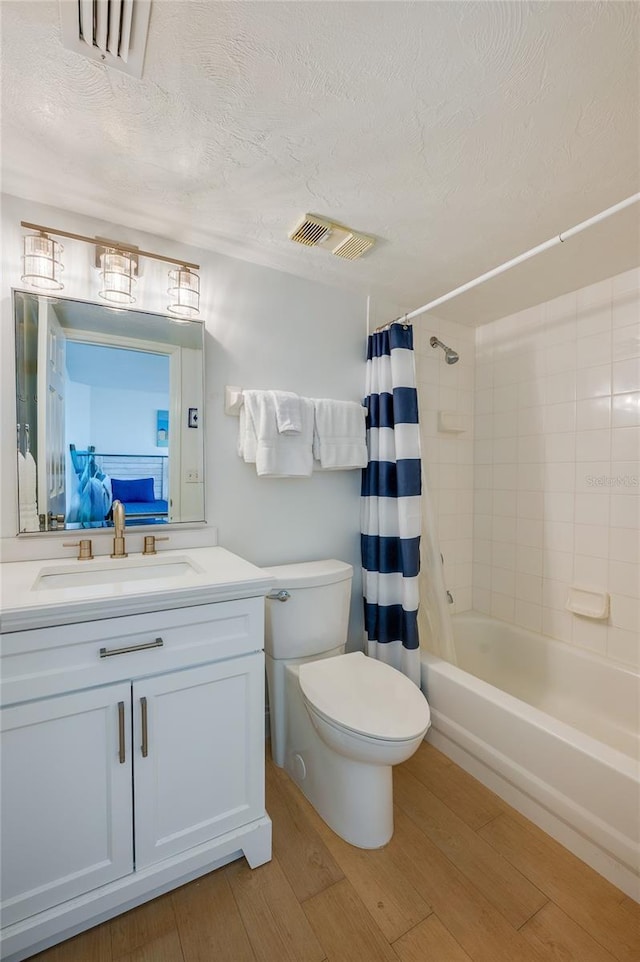 bathroom featuring visible vents, shower / bathtub combination with curtain, toilet, wood finished floors, and vanity