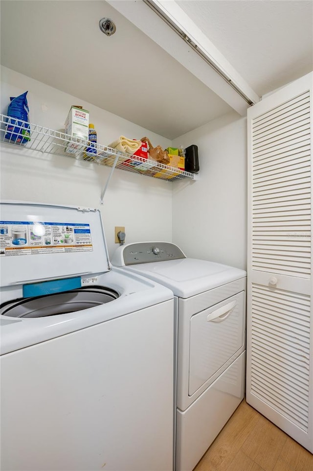 clothes washing area featuring light wood-style floors, independent washer and dryer, and laundry area