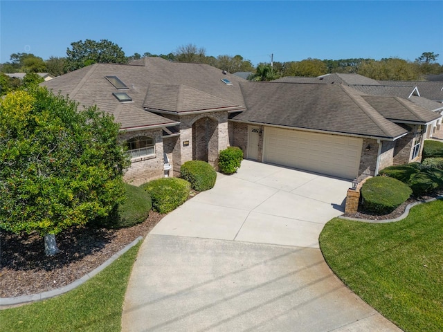 view of front facade with concrete driveway, brick siding, a garage, and a shingled roof