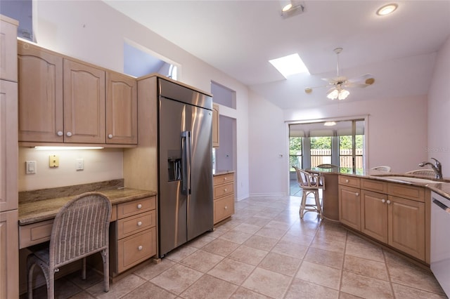 kitchen with stainless steel fridge with ice dispenser, lofted ceiling with skylight, dishwasher, built in desk, and a sink