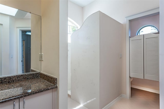 full bath featuring vanity, a skylight, toilet, and baseboards