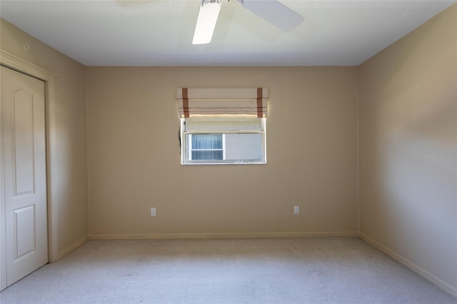 carpeted spare room featuring baseboards and a ceiling fan