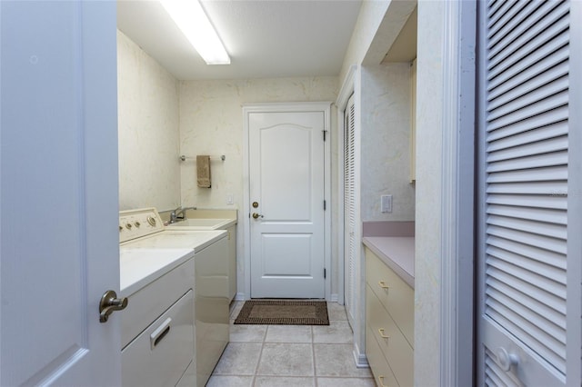 laundry area featuring light tile patterned flooring, independent washer and dryer, cabinet space, and a sink