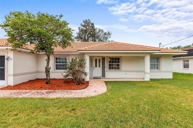 view of front of house with stucco siding, a front lawn, and a tiled roof