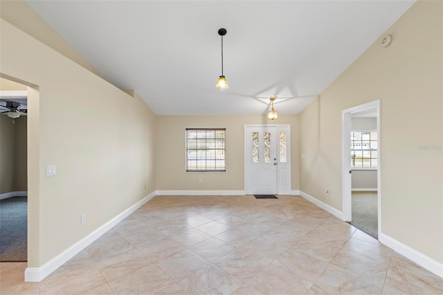 foyer entrance with a wealth of natural light, baseboards, lofted ceiling, and a ceiling fan