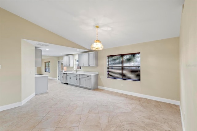 kitchen with lofted ceiling, gray cabinetry, a sink, light countertops, and stainless steel dishwasher