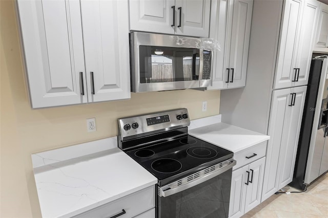 kitchen with appliances with stainless steel finishes, light tile patterned flooring, and white cabinets