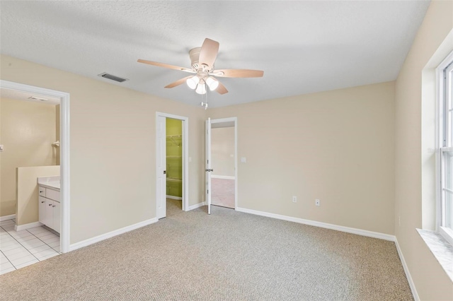 unfurnished bedroom with light carpet, visible vents, a spacious closet, and baseboards