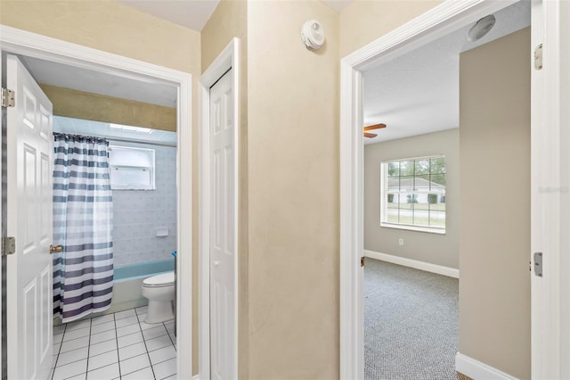 full bath featuring baseboards, ceiling fan, shower / bath combo with shower curtain, tile patterned floors, and toilet