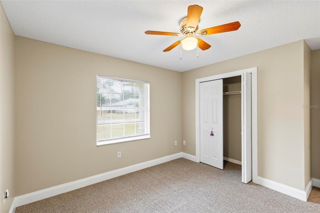 unfurnished bedroom featuring a ceiling fan, light colored carpet, baseboards, and a closet