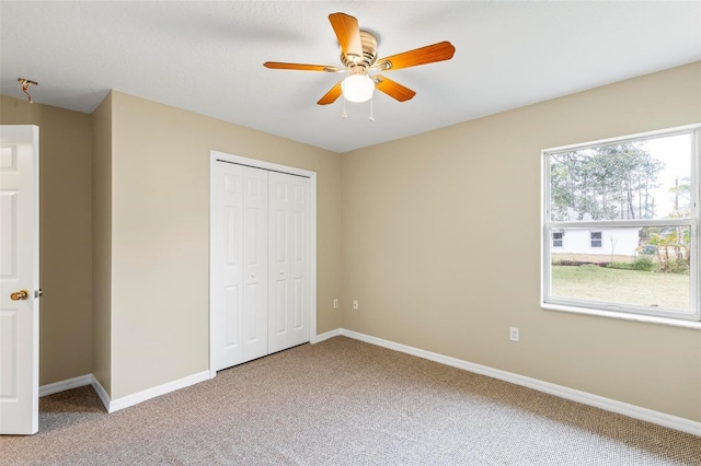 unfurnished bedroom with a closet, a ceiling fan, baseboards, and carpet floors