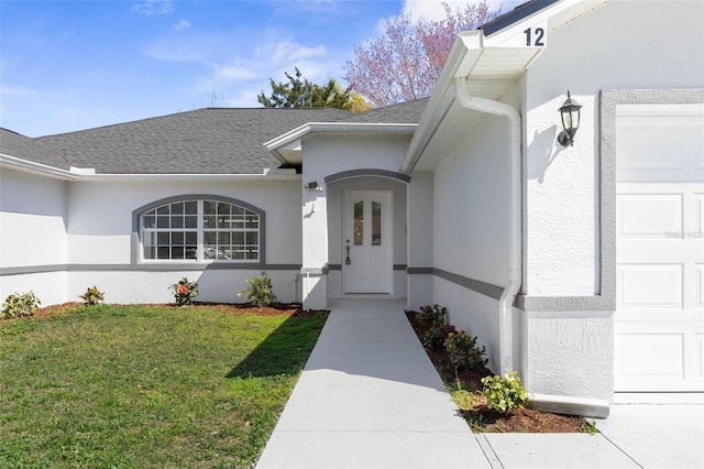 property entrance with a lawn, roof with shingles, and stucco siding