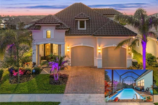 mediterranean / spanish home with a tiled roof, a garage, driveway, and stucco siding