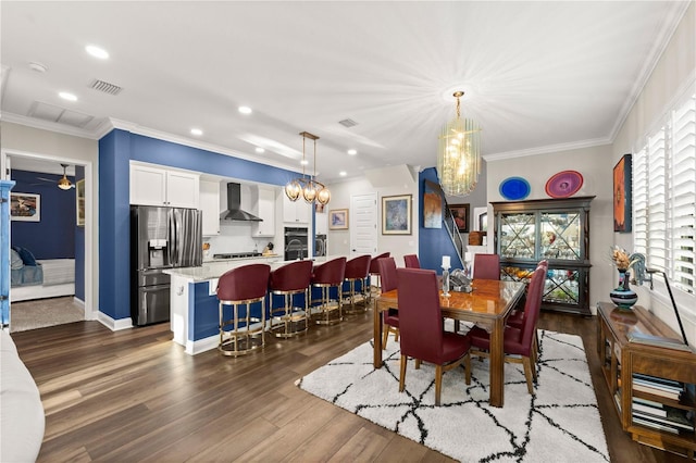 dining space with visible vents, dark wood-type flooring, a chandelier, and ornamental molding