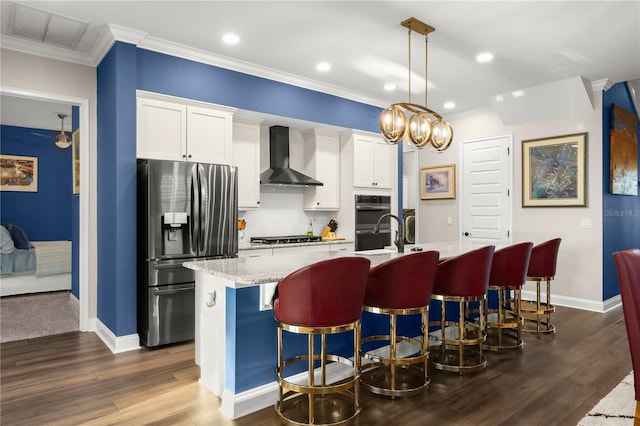 kitchen featuring visible vents, stainless steel fridge with ice dispenser, a kitchen island with sink, crown molding, and wall chimney range hood