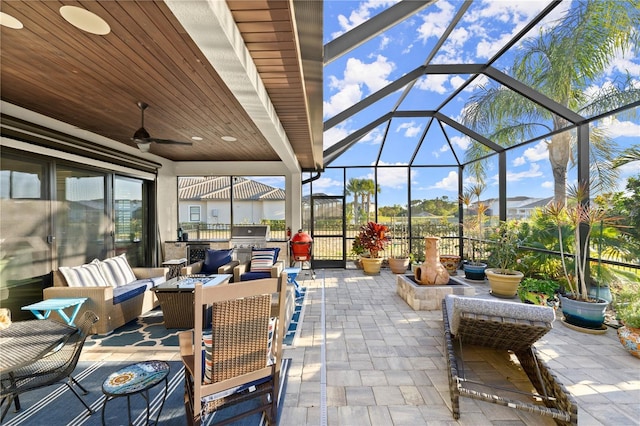 view of patio / terrace with glass enclosure, an outdoor living space, ceiling fan, and an outdoor kitchen