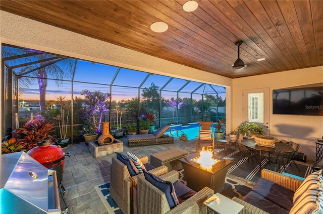 view of patio / terrace with a lanai, an outdoor pool, and an outdoor living space with a fire pit