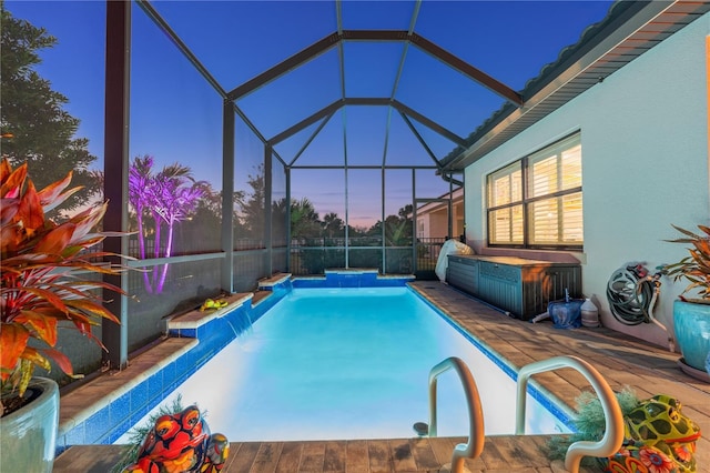 pool at dusk featuring a lanai and an outdoor pool