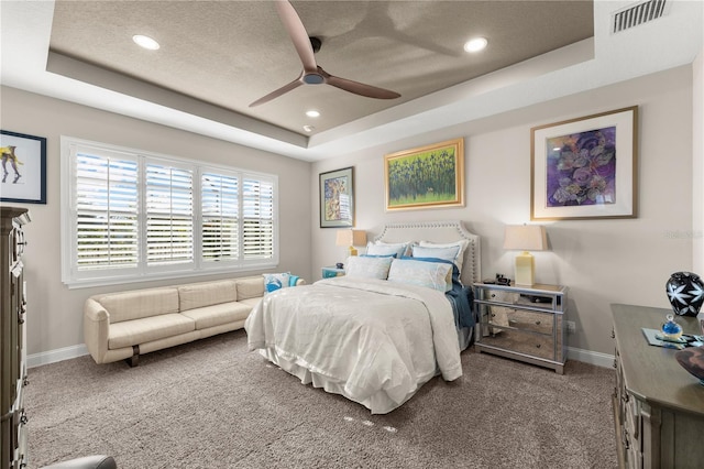 bedroom featuring visible vents, baseboards, a tray ceiling, and carpet floors