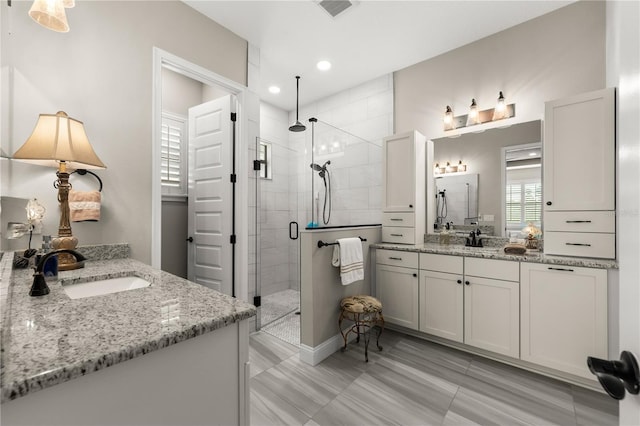 bathroom with a sink, visible vents, two vanities, and a stall shower