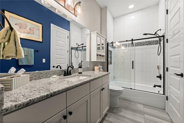 bathroom featuring recessed lighting, enclosed tub / shower combo, toilet, and vanity