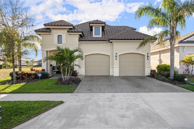 mediterranean / spanish home with a garage, decorative driveway, stucco siding, and a tiled roof