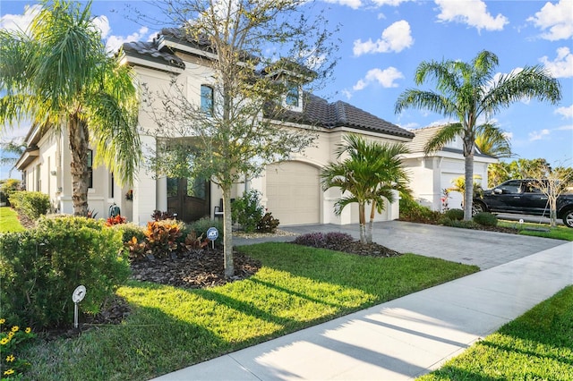 mediterranean / spanish house featuring stucco siding, a front lawn, driveway, and a tiled roof