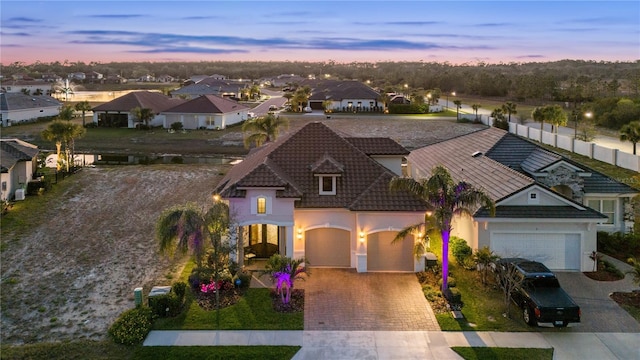 view of front of house with a residential view, a tiled roof, stucco siding, decorative driveway, and a garage