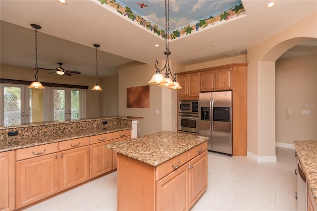 kitchen featuring baseboards, light stone countertops, hanging light fixtures, arched walkways, and stainless steel appliances